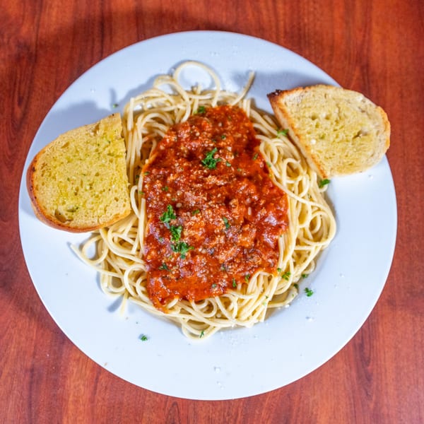 Spaghetti with meat sauce, parmesan cheese, and parsley, served with two slices of garlic bread.