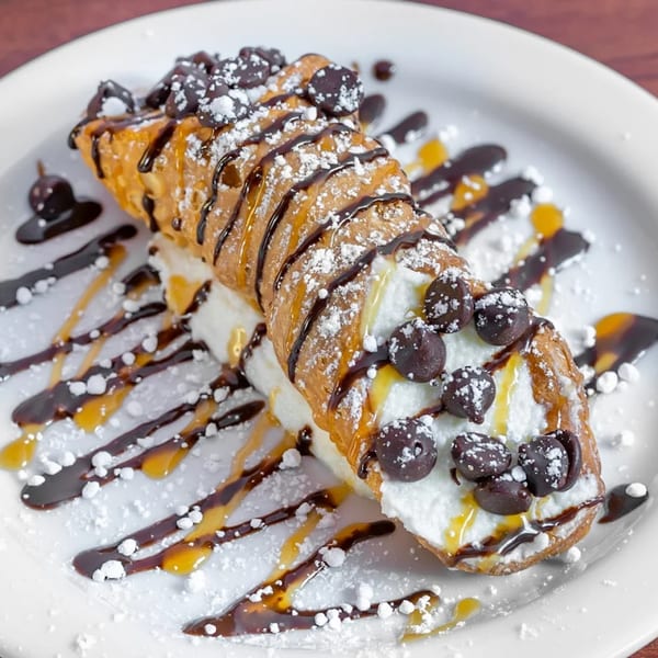 A cannoli from Pizza Bella Italian Bistro, drizzled with chocolate and caramel, topped with chocolate chips.